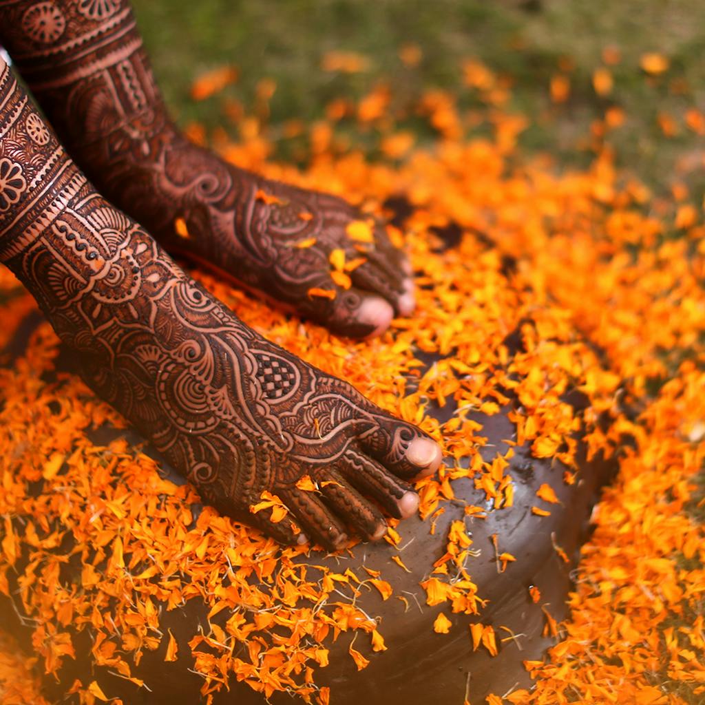 Beautiful henna adorned feet surrounded by vibrant orange marigold petals, symbolizing tradition.