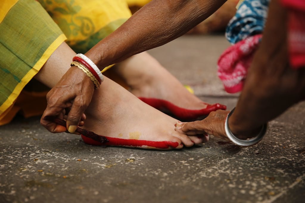 Close-up of a traditional Indian wedding ritual applying red alta to feet, capturing cultural essence.