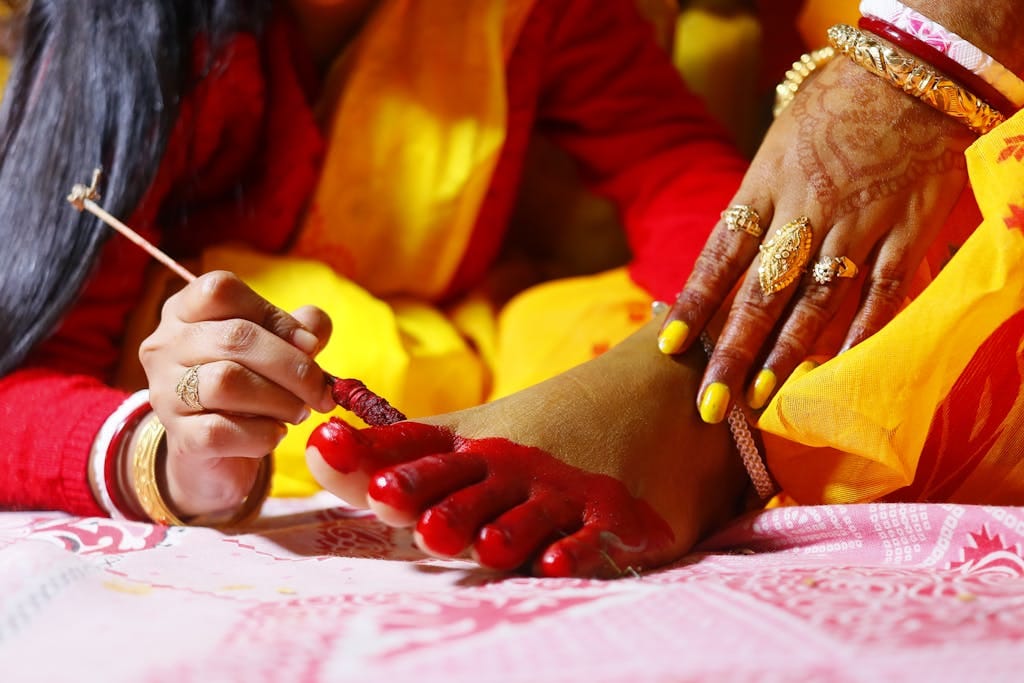 Intricate henna tattoo being applied to an Indian woman's feet, showcasing cultural tradition.
