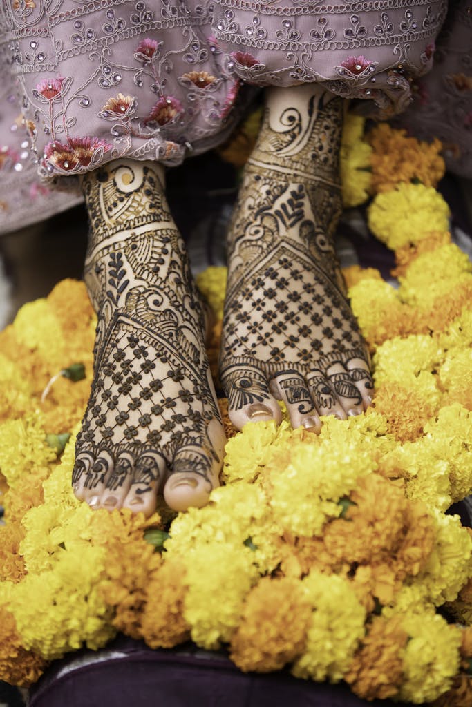 Ornate henna designs on bride's feet surrounded by vibrant marigold flowers, perfect for cultural celebrations.